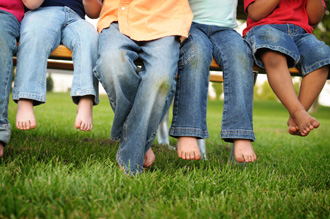 Photo showing legs and feet of children sitting on a bench