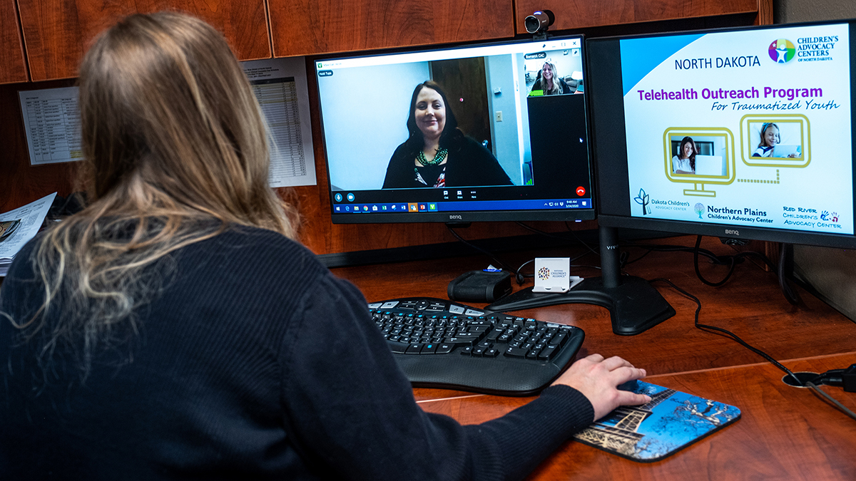 Paula Condol, seated, and Heidi Tupa, onscreen, demonstrate North Dakota's telemental health program.