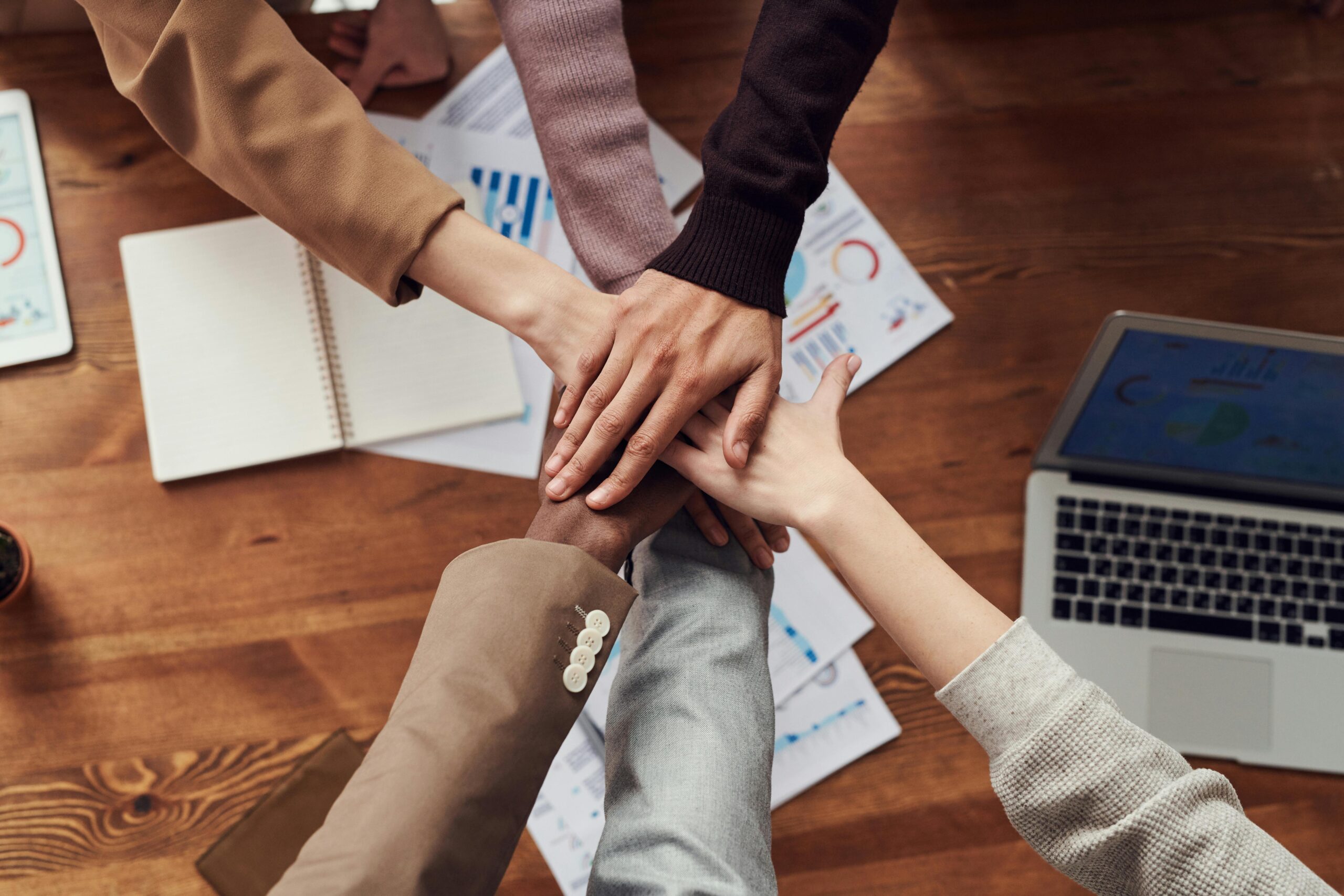 Team stacks hands over work table for camaraderie